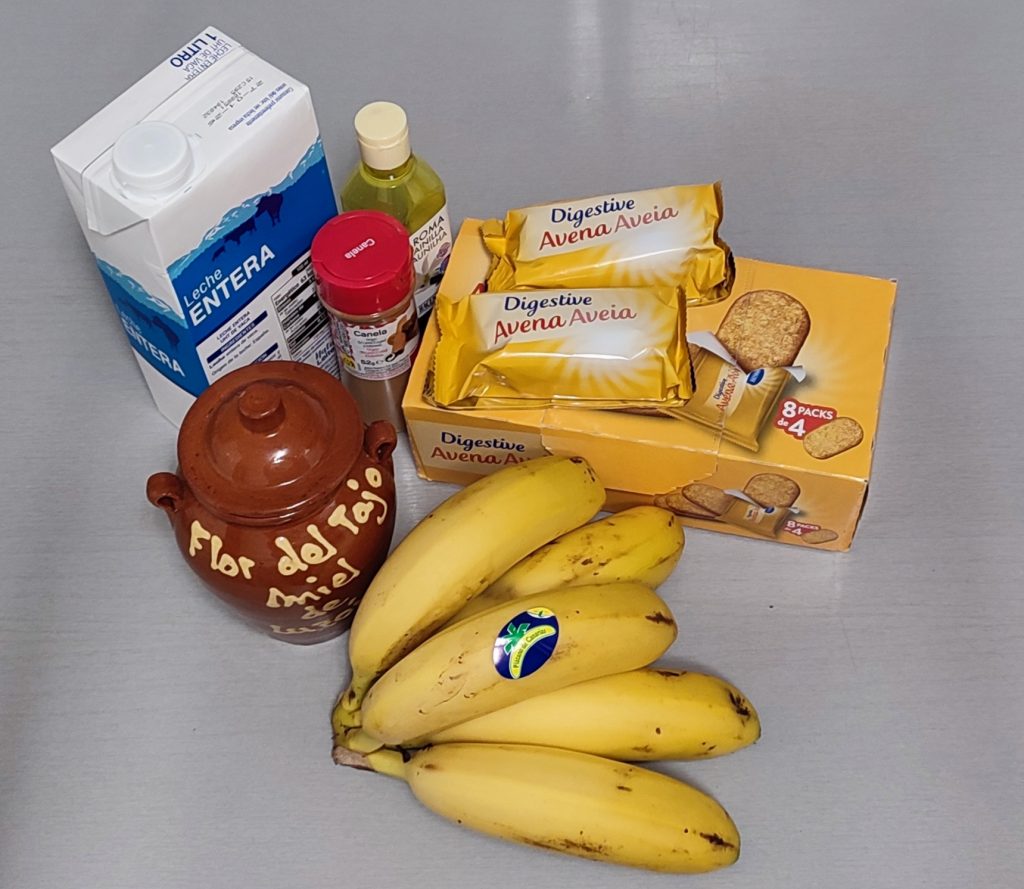 Ingredientes de la poción lunar colocados sobre una encimera gris: leche, plátano, avena, miel y especias.