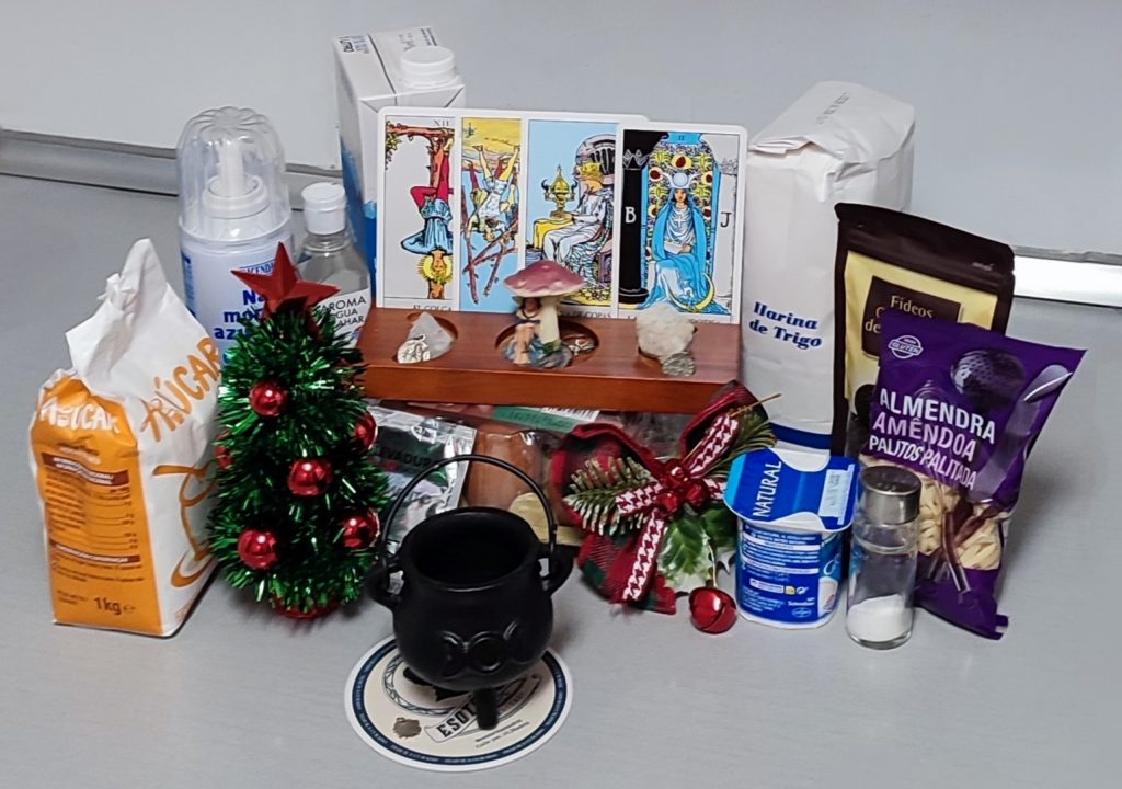 Ingredientes del roscón de Reyes sobre encimera gris, decorados con cartas de tarot, un caldero, un lazo navideño y un árbol de Navidad de mesa.