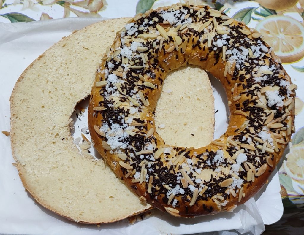 Roscón cortado por la mitad, con las dos partes desplazadas formando una figura similar al infinito, sobre papel de hornear.