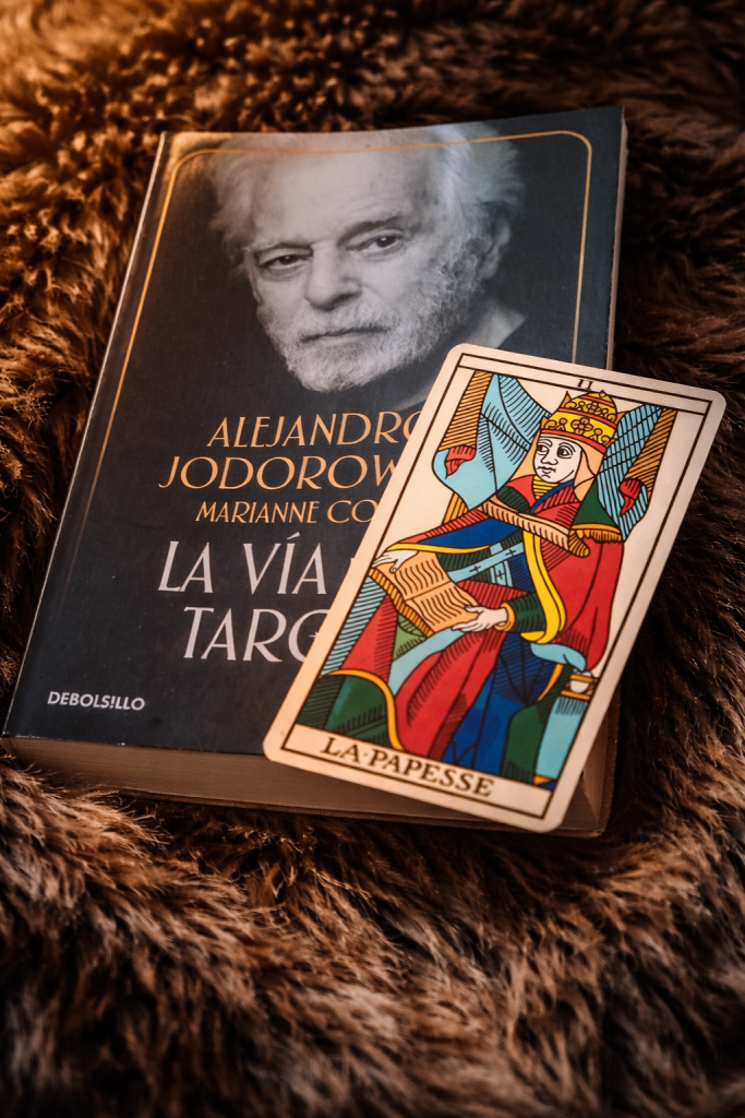 Carta del tarot La Papisa colocada sobre el libro “La Vía del Tarot” de Jodorowsky en un ambiente cálido y simbólico.